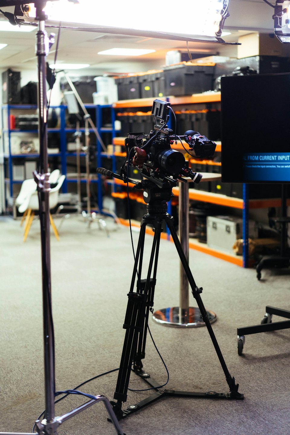 Videocamera professionale su treppiede all'interno di un magazzino di attrezzature.
